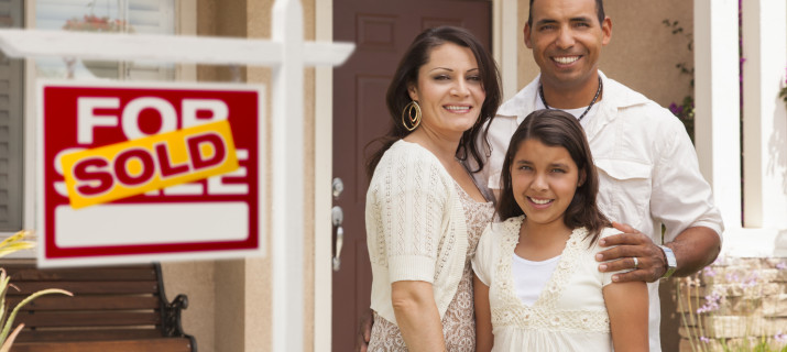 Mother, Father and in Front of Their New Arizona Home with Sold Home For Sale Real Estate Sign.